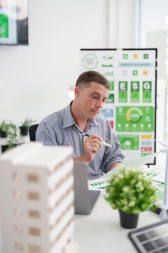 Adult Caucasian man analyzes ESG report for sustainable business growth carbon footprint reduction planning renewable energy solutions and future development