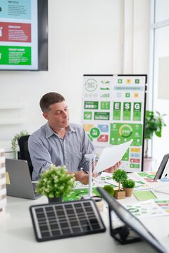 Adult Caucasian man analyzing ESG reports and green business strategies focusing on carbon reduction sustainable energy solutions and environmental impact in a modern office setting