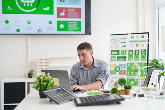 Dedicated adult male professional analyzes ESG data in a modern green business office driving carbon reduction and sustainable environmental solutions