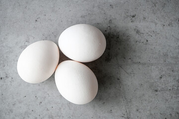 Top view of three white eggs on gray table