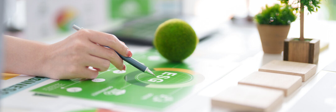Adult hand analyzing ESG report sustainability green business environmental social governance corporate responsibility carbon reduction strategy climate action sustainable development goals