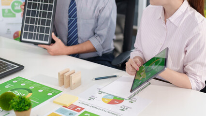 Business professionals discuss ESG strategy sustainability goals and carbon footprint reduction using solar energy solutions in an eco friendly meeting