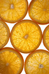 The photograph shows the surface details of a halved orange, studio light from behind.