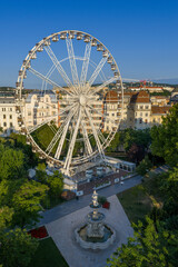 The famous ferris wheel in Budapest included the Danubius fountain. Lush green trees at spring time. Located the Erzsebet park in downtown in capital of Hungary.