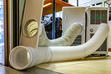 Portable air conditioning unit with exhaust hose placed near an open door in a modern room setting