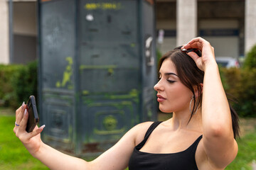 young beautiful happy woman taking selfie with smartphone in city street in perfect youth culture...