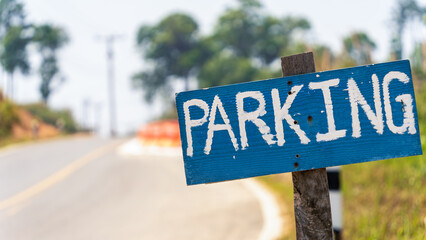 Wooden parking sign beside winding rural road