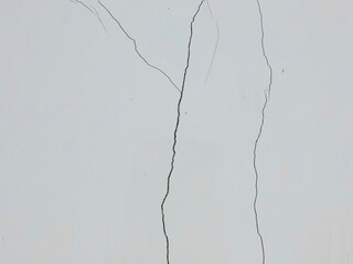 A large crack runs across a white concrete wall, showing signs of structural damage and aging. old wall background