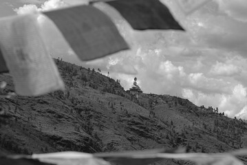 Black and white photo of a Buddha statue and flag on a mountain, Detailed resolution of mountain...