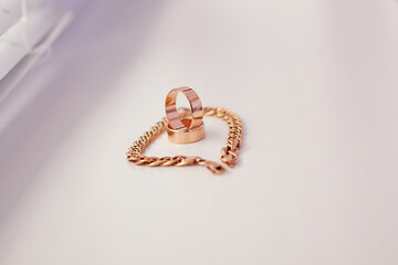 A gold ring and a gold bracelet are placed on a white surface