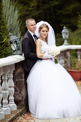 A bride and groom are posing for a picture on a stone wall