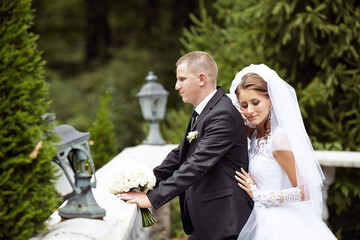 A bride and groom are posing for a picture in front of a statue