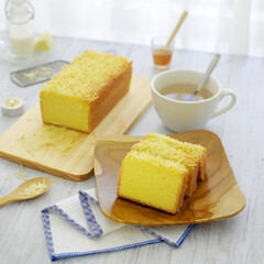 Delicious sliced cheese sponge cake with white tea cup on the table