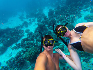 Two divers explore the colorful coral reefs of Thailand while snorkeling. Sunlight penetrates the clear water, illuminating the underwater landscape rich with marine life.