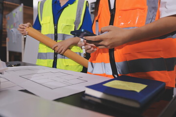 Closeup of team of industrial engineers meeting analyze machinery blueprints consult project on...