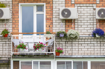 Balcony of an apartment building with a table and chairs decorated with flowers in pots and boxes.