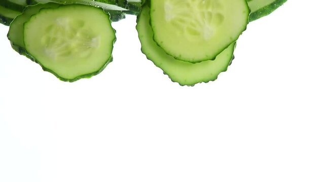 Close-up of fresh cucumber slices against a bright white backdrop.