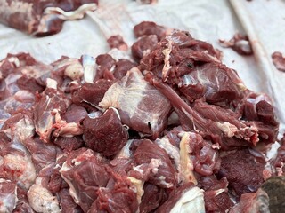 Freshly cut raw beef meat pieces displayed on a white cloth, ready for sale at a traditional market.