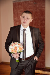 A man in a suit holding a bouquet of flowers