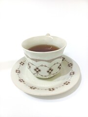 Vintage Floral Teacup Filled with Black Tea on Matching Saucer, Isolated on White Background