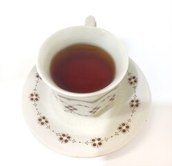 Vintage Ceramic Teacup with Floral Motif Filled with Black Tea on Matching Saucer, Isolated on White Background