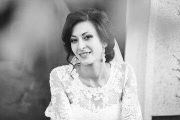 A woman in a white dress is smiling and wearing a veil