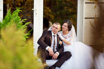 A man and woman are sitting on a bench, the man is wearing a suit and tie