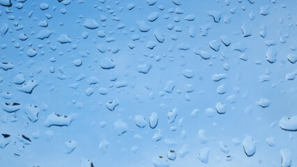 Raindrops on the window. You can see the blue sky through the window. Rainy weather in autumn.