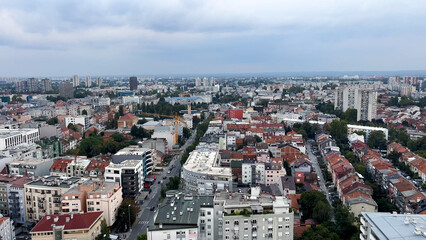Top view of a large European city. Red-tiled roofs and high-rise buildings are visible. Drogues...