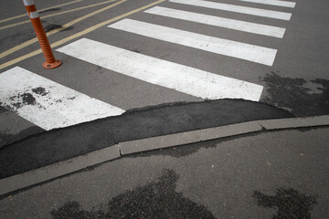 Workers are performing maintenance on a pedestrian crosswalk where the surface has cracked,...