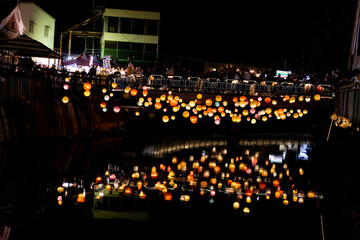 A scenic nighttime view of colorful round lanterns adorning the bridge piers above the water. The...