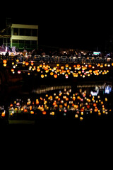 A scenic nighttime view of colorful round lanterns adorning the bridge piers above the water. The...