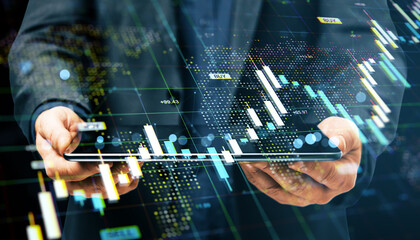 Businessman using tablet with financial data charts and forex market graphs overlayed on dark digital background, showing economic analysis concept.
