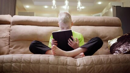 A boy with hearing aids engages with a laptop and tablet, showcasing modern childhood's digital learning and inclusive tech play. Perfect for education and disability awareness content - Powered by Adobe