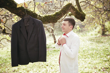 A man is standing in a field with a jacket hanging from a tree