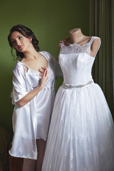 A woman stands next to a wedding dress