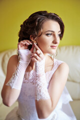 A woman is getting ready for a wedding and is putting on her wedding dress