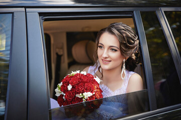 A woman is sitting in a car with a bouquet of red roses in her lap