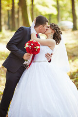 A bride and groom kiss in a forest