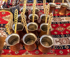 Preparation for brewing strong Turkish coffee. A group of vintage-style hammered copper pots (cezve) on a traditional textile background.Equipment for brewing traditional hot coffee.