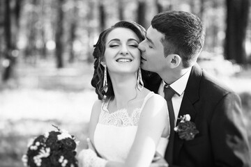 A bride and groom are kissing each other in a forest