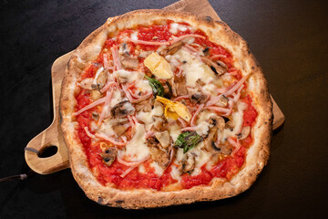 hot italian fresh baked capricciosa pizza on black background