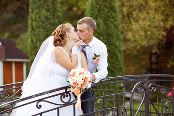A bride and groom kiss on a bridge