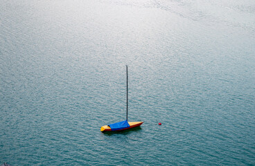 Yellow sailboat with blue cover floating on alpine lake in the Austrian Alps 