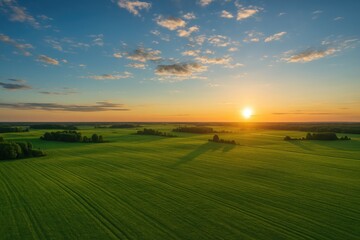 Aerial landscape shot capturing vibrant green fields and a clear blue sky just before sunset