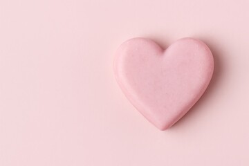 Fototapeta premium Pink heart-shaped soap bar on a light pink background with ample space for text.