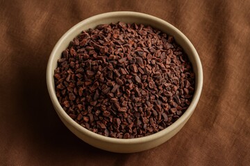 Chocolate nibs in a bowl placed on a rustic fabric surface