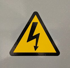 Señal de alto voltaje. Símbolo de peligro. Flecha negra en un triángulo amarillo. Señal de advertencia en puerta de cuarto de electricidad 