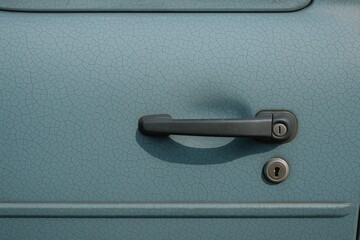 Close-up of a damaged blue-grey car door with a crack