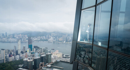 Successful businesswoman in suit standing in office looking through window at big city buildings